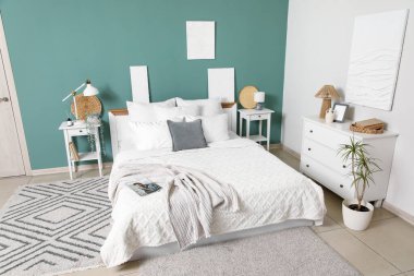 Yatak odasının iç kısımlarında yeşil duvarın yanında büyük rahat yatak ve komodinleri var.