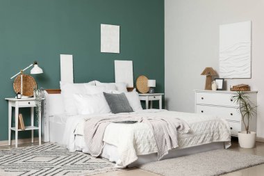 Yatak odasındaki yeşil duvarın yanında büyük, rahat yataklar ve komodinlerin yanında.