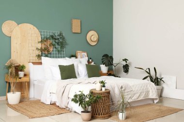 Yatak odasının iç kısımlarında büyük konforlu yataklar, masalar ve bitkiler var.