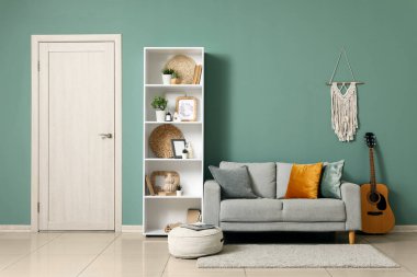 Beyaz kapı, raf ünitesi ve modern odanın içindeki yeşil duvarın yanındaki kanepe.