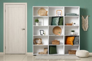 Beyaz kapı, raf ünitesi ve modern odanın içindeki yeşil duvarın yanında pouf.