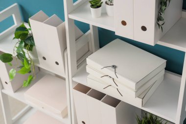 Ofis dosyalarına ve mavi duvarın yakınındaki evlere sahip raf ünitesi, yakın plan.