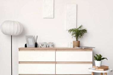 Çekmeceler, masa ve zemin lambası. Odanın içindeki beyaz duvarın yanında.