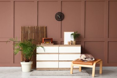 Çekmeceler, katlanan ekran ve ayaklar odanın içindeki kahverengi duvarın yanında.