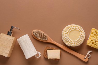 Masaj vücut fırçaları, banyo süngerleri ve kahverengi arka planda bir şişe kozmetik ürünü içeren kompozisyon, yakın plan.