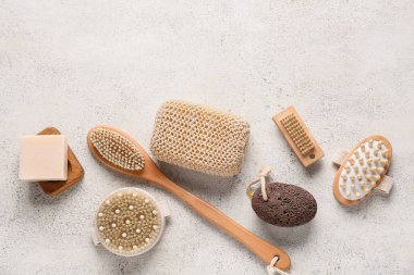 Beyaz grunge arka planında farklı masaj vücut fırçaları, sünger taşı ve sabun kalıbı olan kompozisyon, yakın plan.