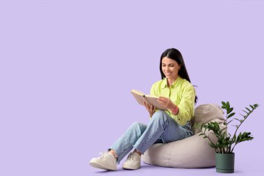 Güzel bir kadın, arkaplanda leylak arkaplanına karşı armut çantası kitabı okuyor.