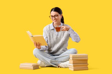 Sarı arka planda çay fincanı okuyan güzel bir kadın.