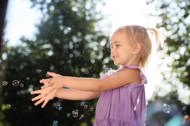 Parkta sabun köpüğü olan sevimli küçük kız.