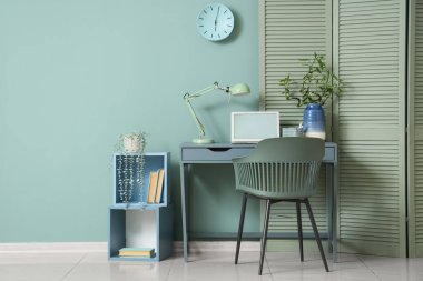 Oturma odasının içinde masa, katlama ekranı ve nane duvarının yanında raf ünitesi var.