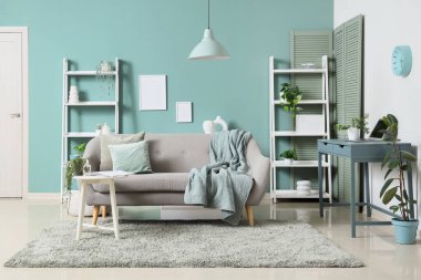 Konforlu kanepe, masa ve raflar oturma odasının içindeki nane duvarının yanında.