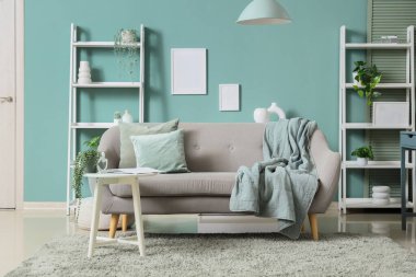 Konforlu kanepe, masa ve raflar oturma odasının içindeki nane duvarının yanında.