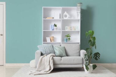 Nane duvarının yanında rahat kanepesi ve raf ünitesi olan oturma odasının içinde.