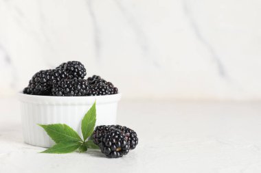 Beyaz arka planda olgun böğürtlenlerle dolu bir kase