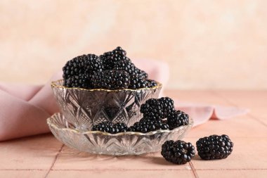 Cam kase ve tabak bej fayansların üzerinde olgun böğürtlenlerle