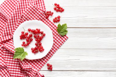 Beyaz ahşap arka planda taze kırmızı üzümlü tabaka, yakın plan.