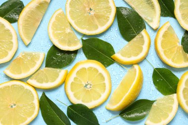 Taze olgun limon dilimleri ve mavi arka planda yapraklar
