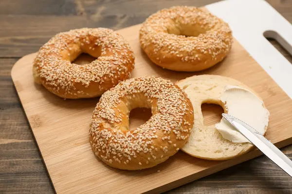 Tahta arka planda susam tohumlu lezzetli simit tahtası, yakın plan.