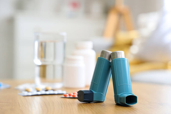 Современные ингаляторы, таблетки и лекарства на кофейном столике в гостиной, крупный план