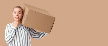 Bej arka planda bir paket kutusu olan şaşırmış genç bir kadın.