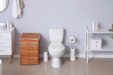 Tuvalet klozeti ve hasır sepeti olan ışık tuvaletinin içinde.