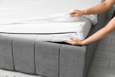 Yumuşak ortopedik şilteli kadın evde yatak yapıyor, yakın plan.