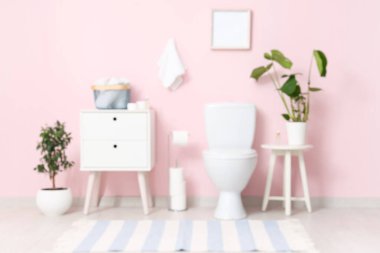 Tuvalet, komodin ve tuvaletteki pembe duvarın yanındaki bitkiler.