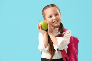 Mavi arka planda elma olan küçük okul kızı.