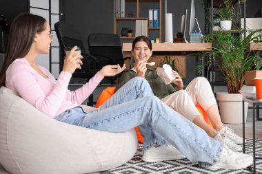 Kadın programcılar ofiste puf minderlerle yemek yiyorlar.