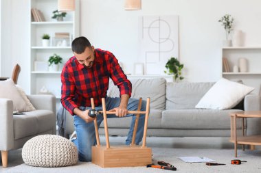 Evinde ahşap masa montajı yapan genç bir adam.