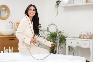 Güzel, genç, mutlu kadın banyoda oturuyor.