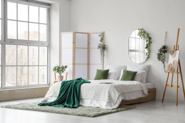 Rahat yatak odasının içinde ayna, resim sehpada ve katlanan ekranda.