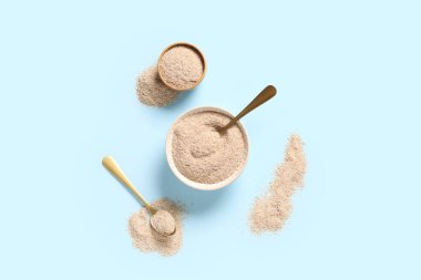 Mavi arka planda psyllium kabuk pudrası olan kaseler ve kaşıklar