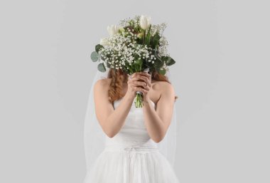 Beyaz gelinlik içinde, açık arkaplanda çiçekler olan güzel bir gelin.