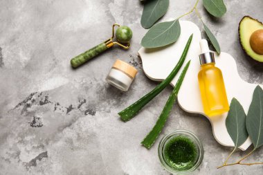 Kozmetik ürün şişesi, alçı podyum ve gri grunge arka plandaki malzemeler, yakın plan.