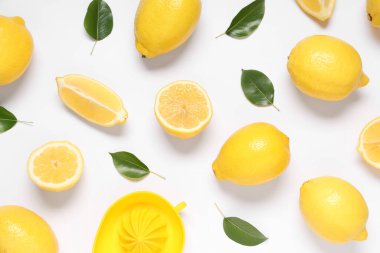 Taze taze limonlar ve gri arka planda yapraklar ve meyve sıkacağı.