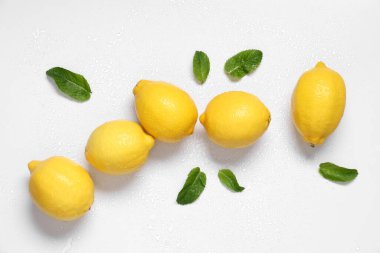 Taze olgun limonlar ve gri arka planda yapraklar