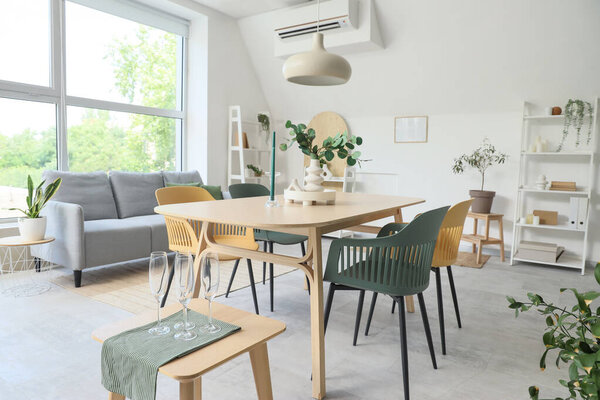 Interior of light room with dining table, sofa and plants