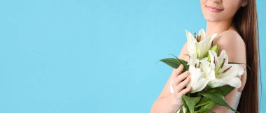 Mavi arka planda beyaz zambak çiçekleri olan güzel, genç, mutlu bir kadın.