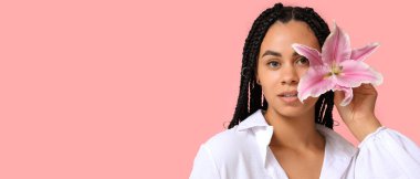 Pembe arka planda zambak çiçeği olan güzel bir Afro-Amerikalı kadın.