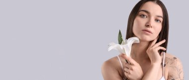 Young woman with white lily on light background, closeup