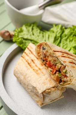 Yeşil ahşap arka planda marullu lezzetli bir shawarma tabağı.