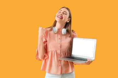 Sarı arka planda boş dizüstü bilgisayarı olan mutlu kadın programcı.