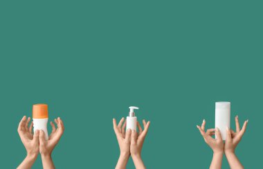 Yeşil arka planda güneş kremi şişeleri olan kadın elleri