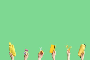 Hands with school accessories on green background