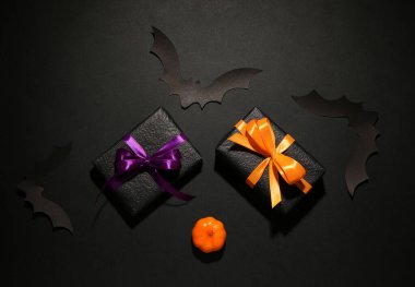 Cadılar Bayramı partisi için balkabaklı kağıt yarasalar ve siyah arka planda hediye kutuları.