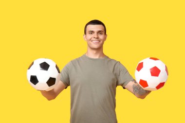 Sarı arka planda futbol topları olan yakışıklı genç adam.