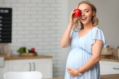 Mutfakta elmalı hamile bir kadın.