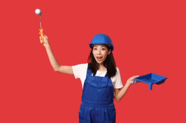 Kırmızı arka planda silindirli ve tepsisi olan Asyalı kadın şokta.