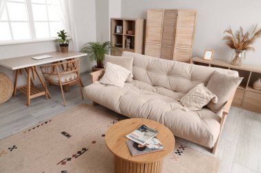 Oturma odasının içinde bej kanepe ve masalar var.